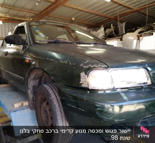 רכב ירוק על מעלית במוסך לתיקון פחחות
